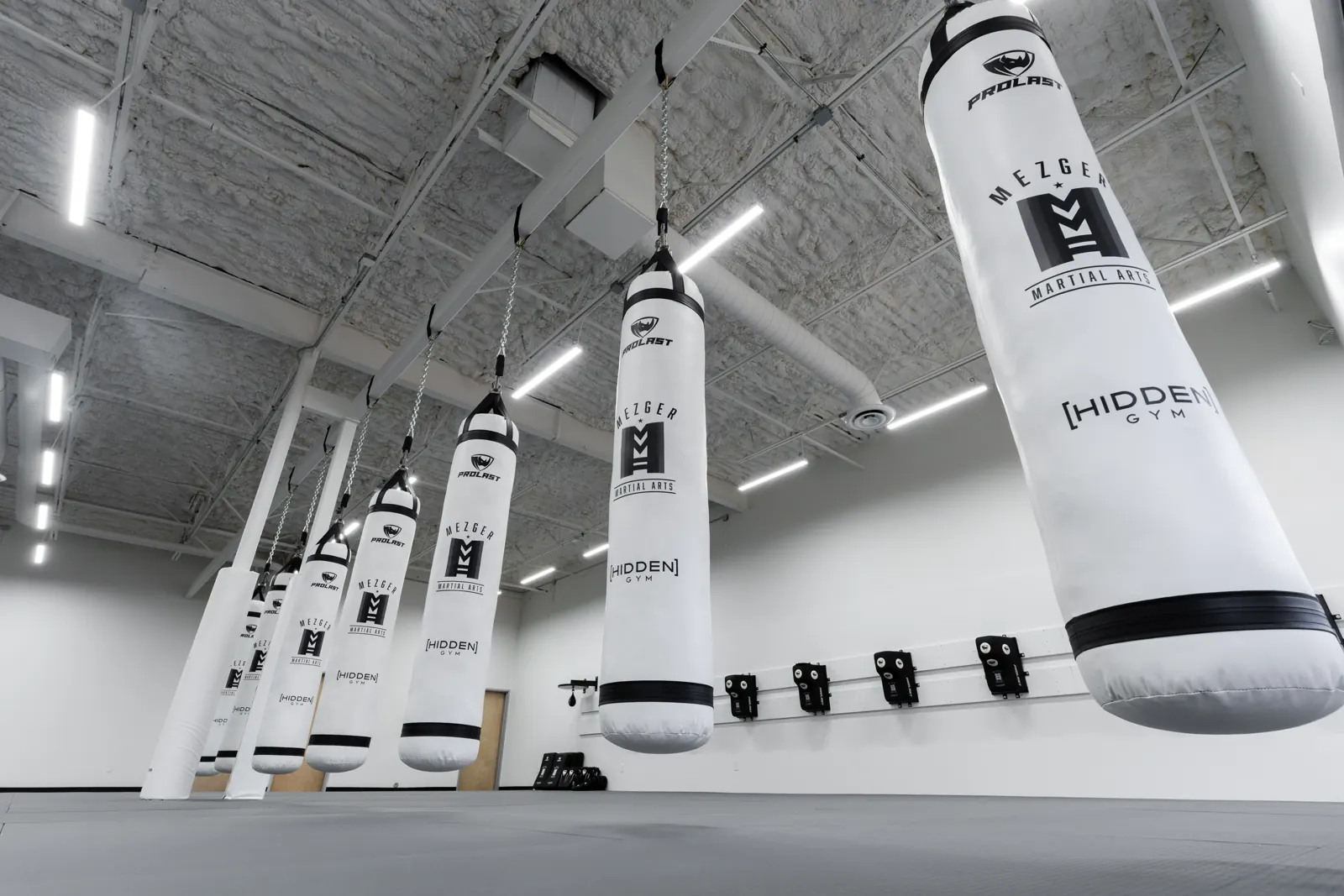Mezger Martial Arts branded heavy bags on the training floor